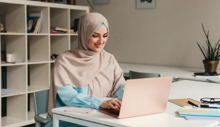 Student preparing and reviewing assignment papers using laptop